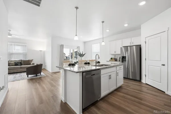 a kitchen with stainless steel appliances granite countertop a sink a stove a refrigerator and island with wooden floor