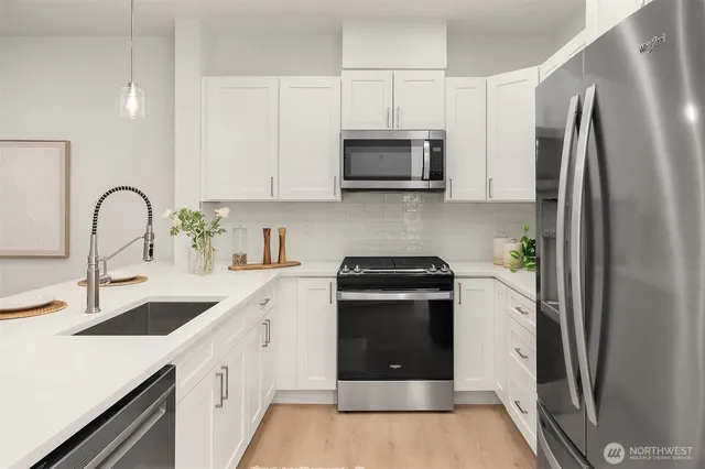 a kitchen with stainless steel appliances a stove a sink a refrigerator and cabinets