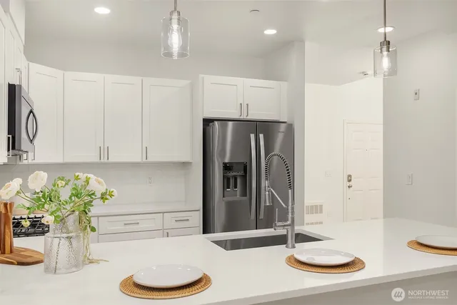 a kitchen with stainless steel appliances kitchen island granite countertop a refrigerator and a sink
