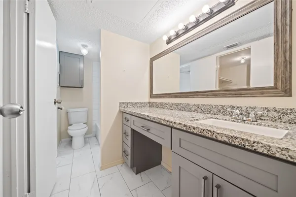 a bathroom with a granite countertop sink a toilet and a mirror