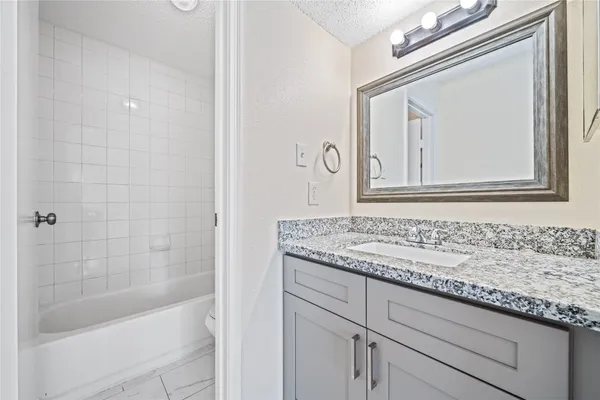 a bathroom with a granite countertop sink mirror and a bathtub