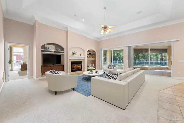 a view of a livingroom with a fireplace a chandelier and windows