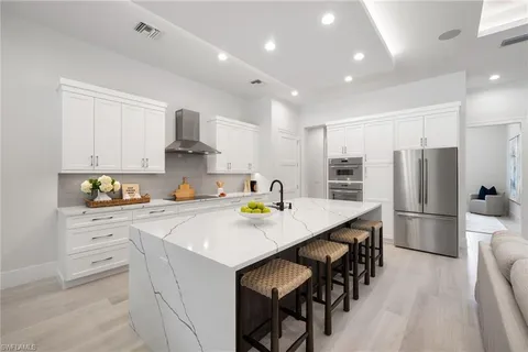 a kitchen with stainless steel appliances a white table chairs and a refrigerator