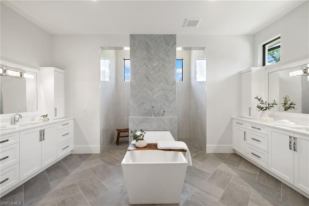 4751 1st Avenue Southwest Naples, FL 34119 - Photo 23 of 36 a spacious bathroom with double vanity sink a two mirror a bathtub and a toilet