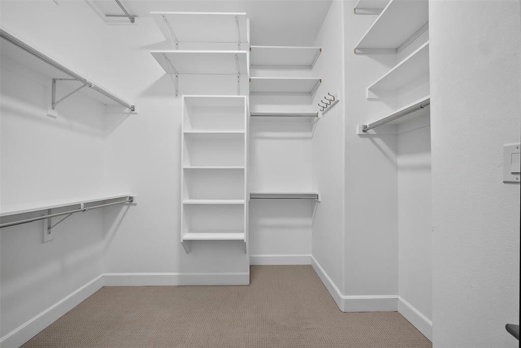 5015 Meridian Lane, Unit 2102 Addison, TX 75001 - Photo 23 of 36 Spacious walk-in closet featuring white wall shelving, metal hanging rods, built-in cubbies, and neutral-toned carpeting