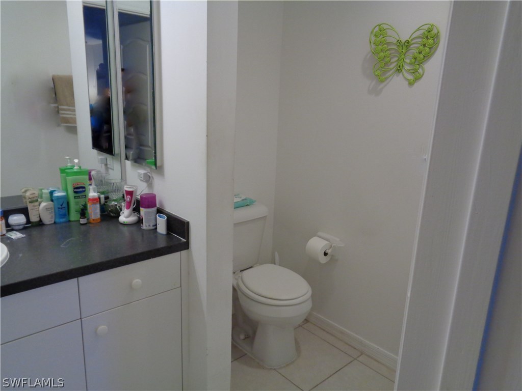 2512 53rd Street West Lehigh Acres, FL 33971 - Photo 21 of 25 a bathroom with a granite countertop sink a toilet and a mirror