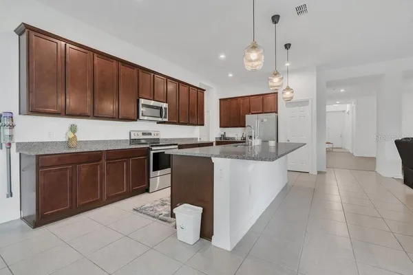 a kitchen with stainless steel appliances granite countertop a stove a sink a microwave and a refrigerator