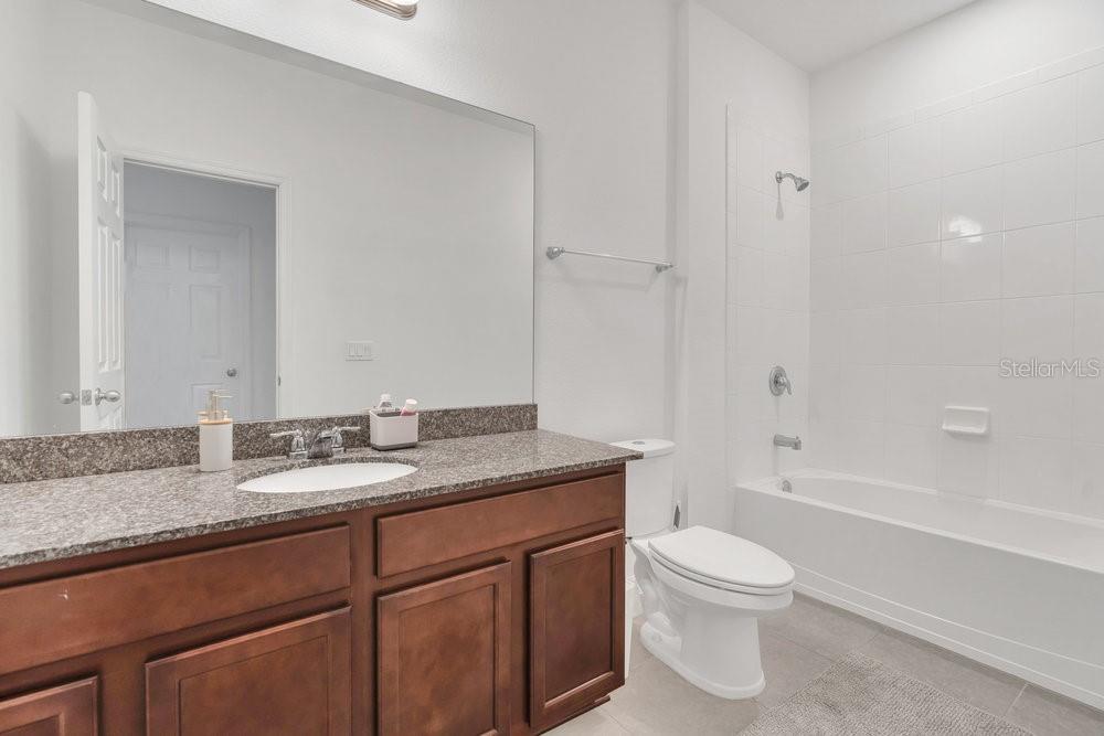12880 Westside Vlg Loop Windermere, FL 34786 - Photo 24 of 42 a bathroom with a granite countertop toilet sink and mirror