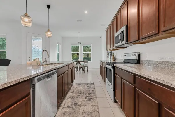 a kitchen with kitchen island granite countertop a sink a counter top space cabinets and stainless steel appliances