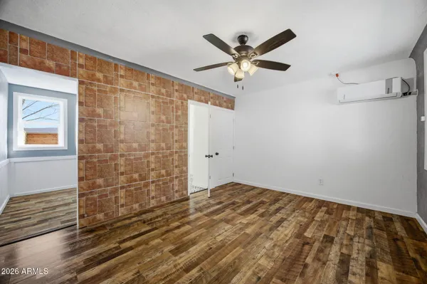 a view of empty room with wooden floor and fan