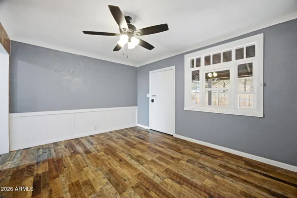 a view of an empty room with window and ceiling fan