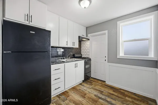 a kitchen with granite countertop white cabinets and refrigerator