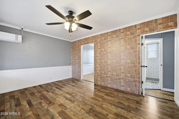 an empty room with wooden floor fan and windows