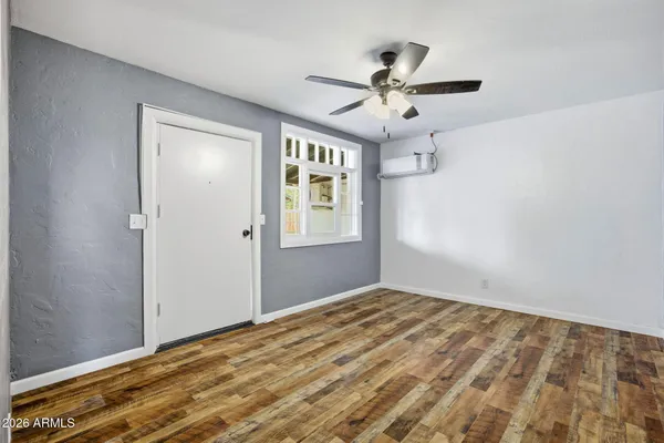 a view of an empty room with wooden floor and a window