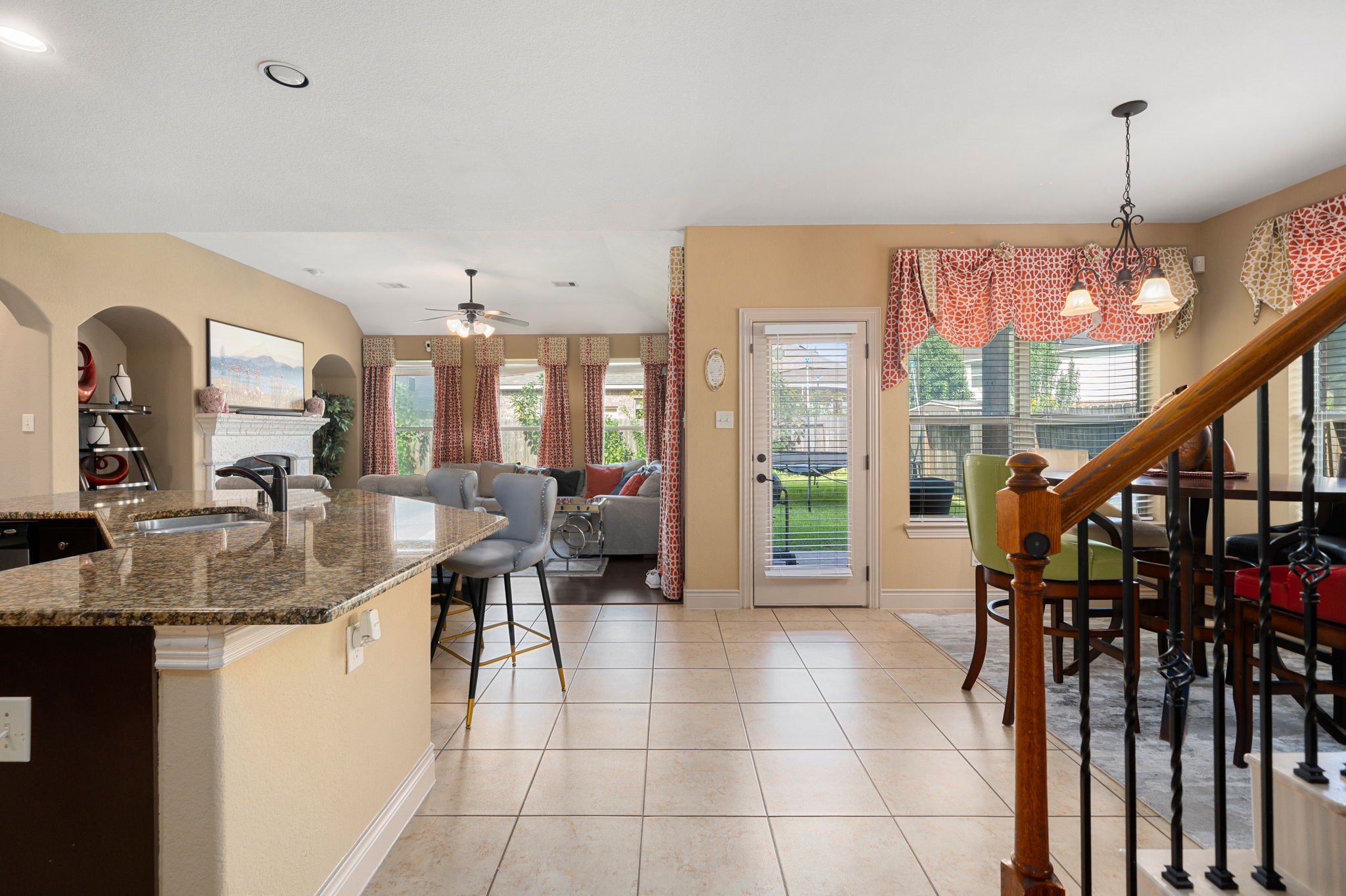 5110 Ruby Rock Way Richmond, TX 77407 - Photo 13 of 27 This photo showcases an open-concept living space with a modern kitchen featuring granite countertops, a cozy living area with large windows and abundant natural light, and a dining area with view of the backyard.