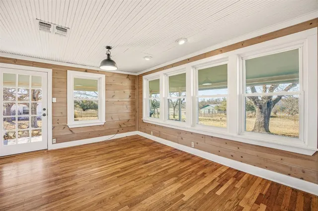a view of an empty room with a window and wooden floor