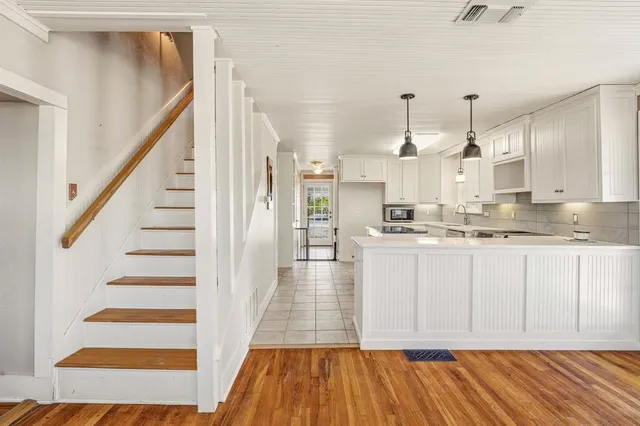 a view of large kitchen with cabinets and wooden floor