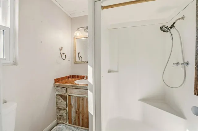 a bathroom with a granite countertop sink a mirror and shower