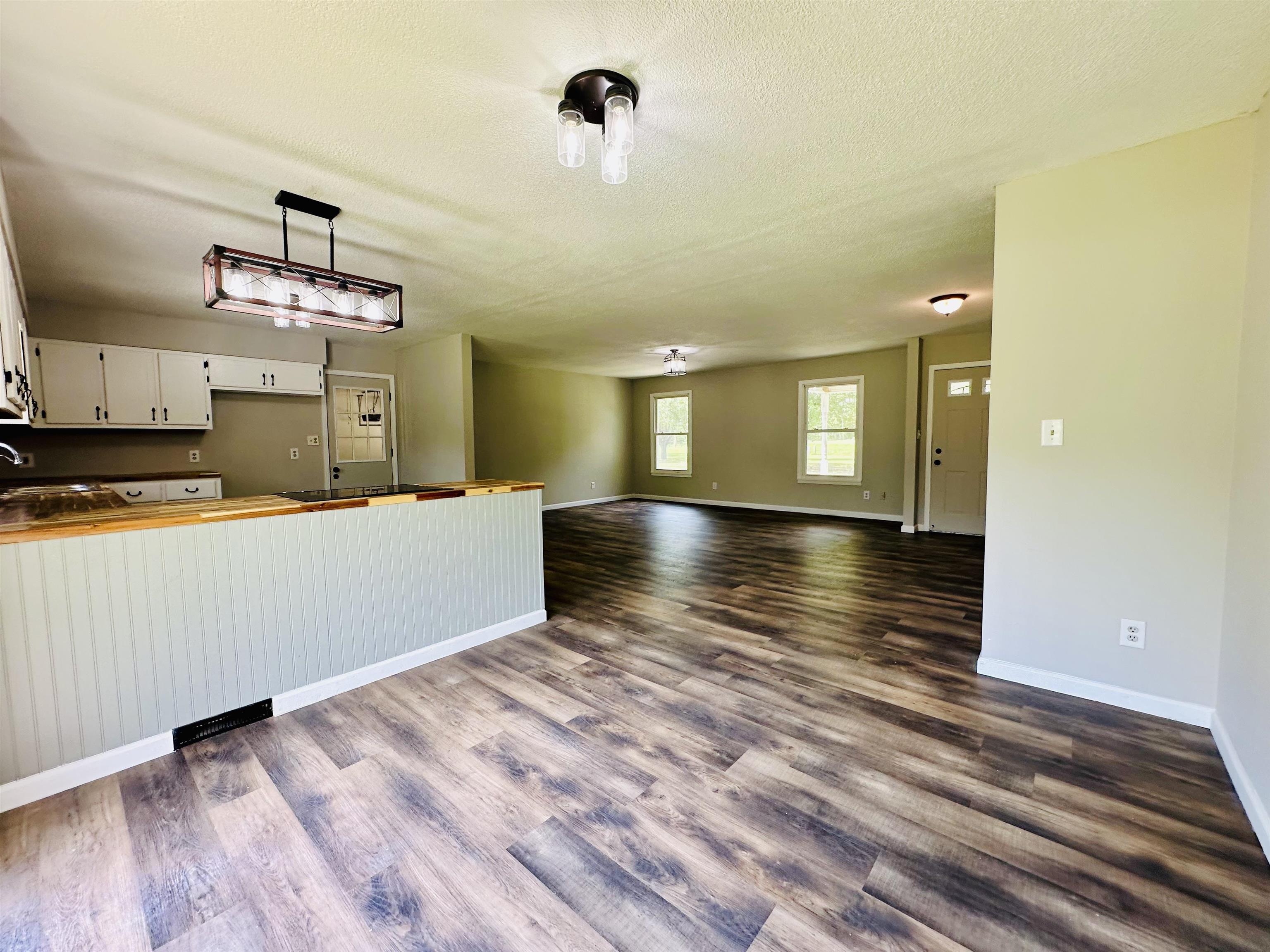 287 Gilchrist Stantonville Road Adamsville, TN 38310 - Photo 29 of 29 Kitchen featuring dark wood-type flooring, a textured ceiling, white cabinetry, and open floor plan