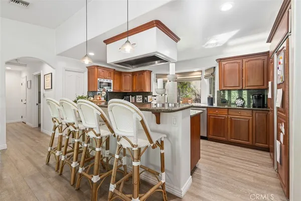 a very nice looking open dining room with kitchen island stainless steel appliances a sink and wooden floor