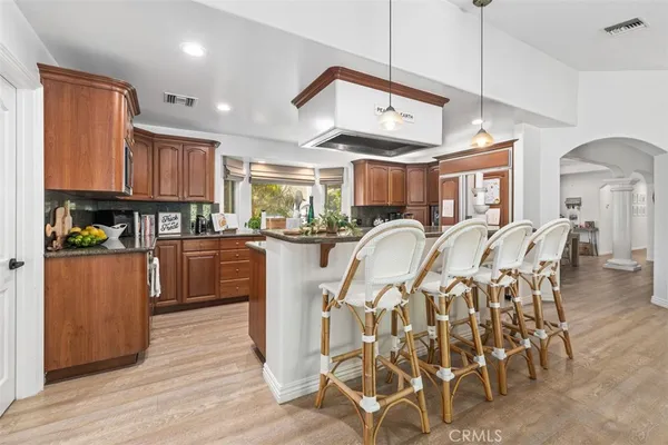 a kitchen with stainless steel appliances kitchen island granite countertop a table chairs and a refrigerator