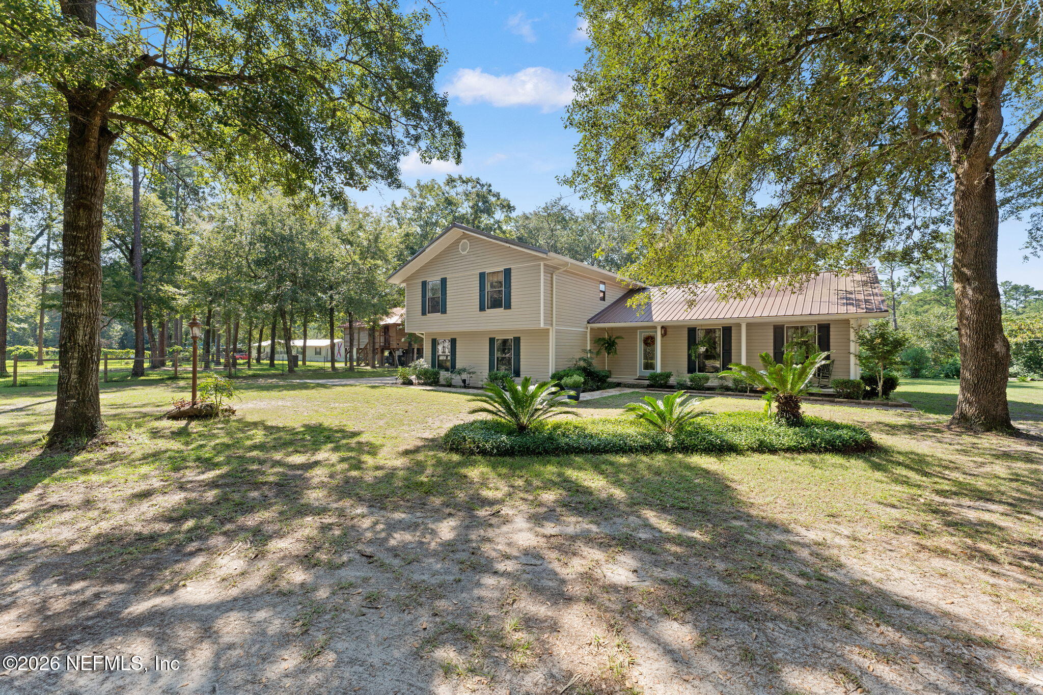 a view of a house with a big yard and large trees
