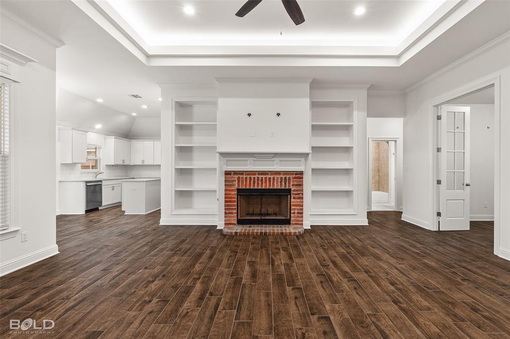304 Prien Lk Loop Bossier City, LA 71111 - Photo 11 of 39 Living area featuring wood-finish flooring, a brick fireplace with a white mantel, and built-in shelving
