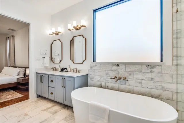 a bathroom with a double vanity sink mirror and bathtub