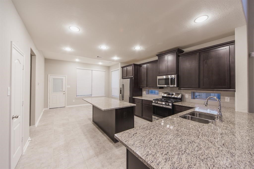 3219 Montclair Orchard Trace Spring, TX 77386 - Photo 9 of 27 a kitchen with stainless steel appliances granite countertop a sink stove and refrigerator