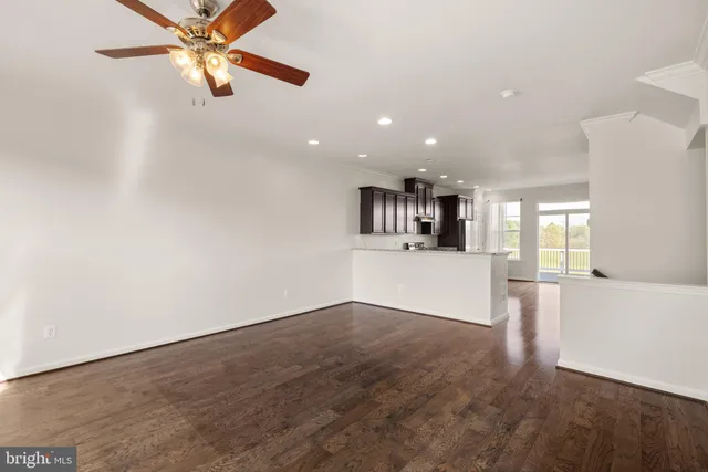 an empty room with ceiling fan and windows