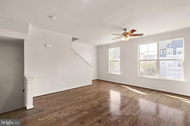 an empty room with windows and chandelier fan