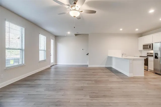 a view of an empty room with window and wooden floor
