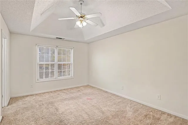 an empty room with a chandelier fan and window