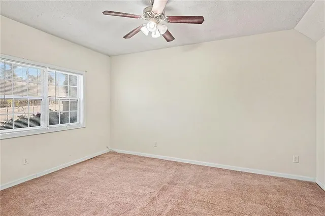 an empty room with windows and fan