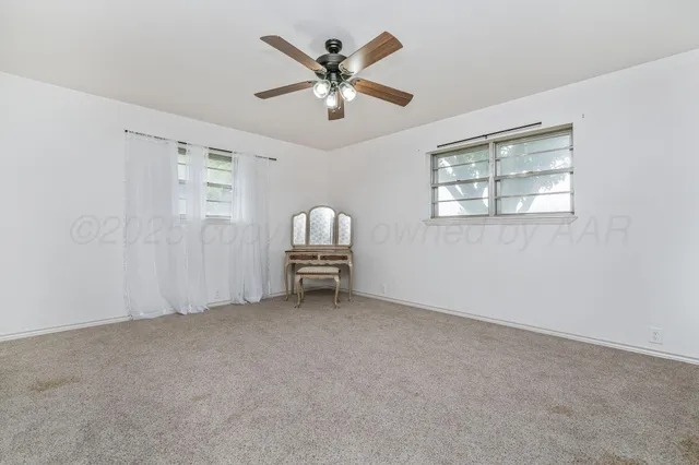 an empty room with windows and ceiling fan