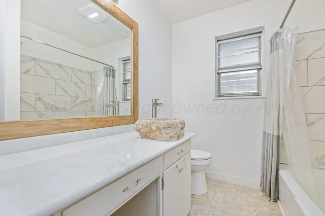 a bathroom with a granite countertop sink toilet and mirror