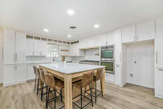 a kitchen with a table a refrigerator a cabinets and stools