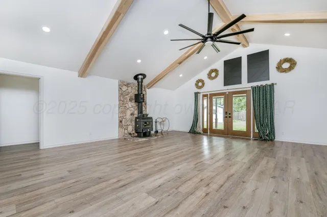 a view of an empty room with window and wooden floor