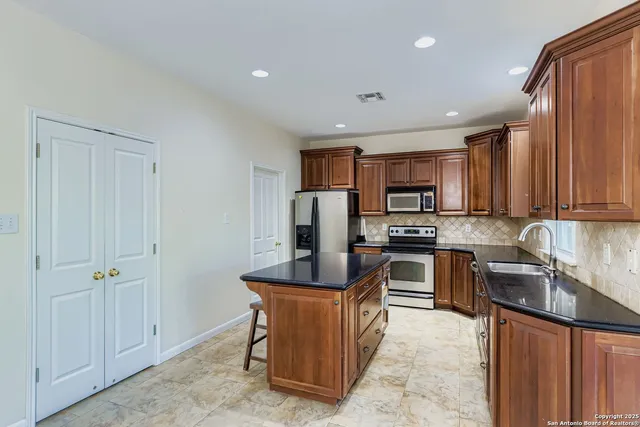 a kitchen with stainless steel appliances granite countertop a stove top oven a sink dishwasher a refrigerator and a microwave