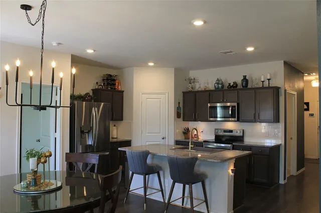 a kitchen with stainless steel appliances kitchen island granite countertop a refrigerator a stove a microwave a sink and a refrigerator