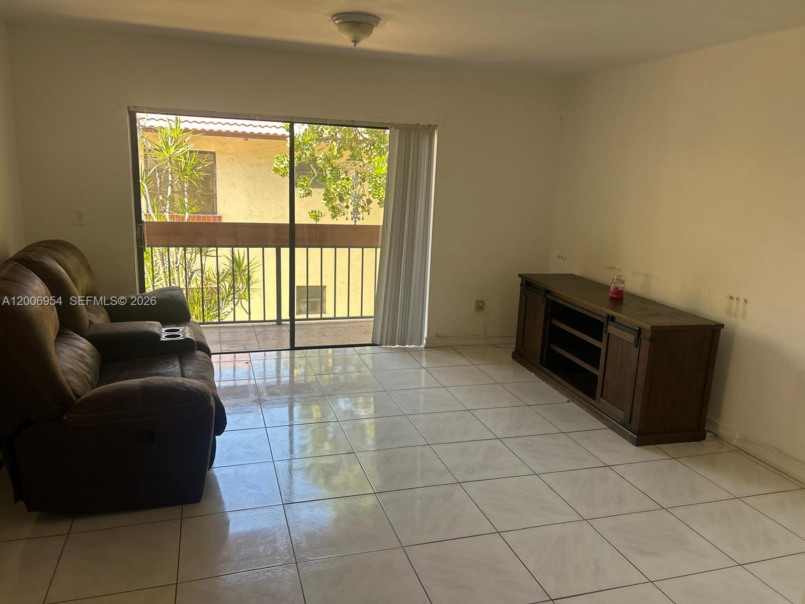 8620 Southwest 149th Avenue, Unit 418 Miami, FL 33193 - Photo 7 of 9 a living room with furniture and a floor to ceiling window
