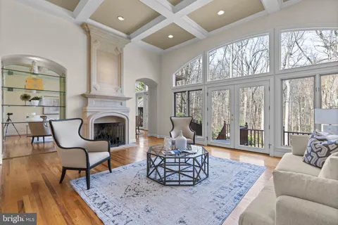 a living room with stainless steel appliances granite countertop furniture a fireplace a rug kitchen view and a large window