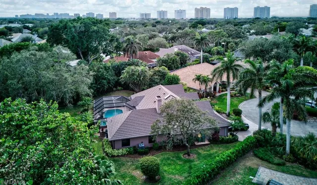 an aerial view of a house with yard and trees in the background