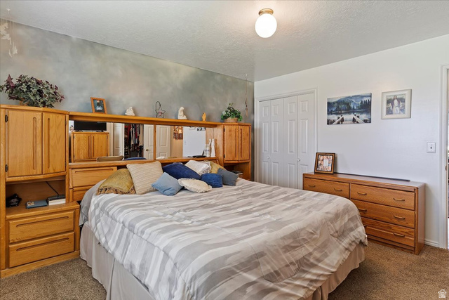 5321 South 3100th Street West Roy, UT 84067 - Photo 39 of 64 Spacious bedroom featuring textured wall treatment, neutral-toned carpeting, and a built-in closet with bifold doors