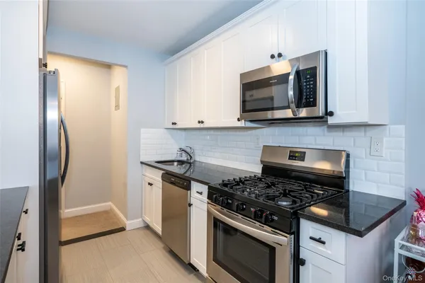 a kitchen with stainless steel appliances white cabinets and a stove top oven