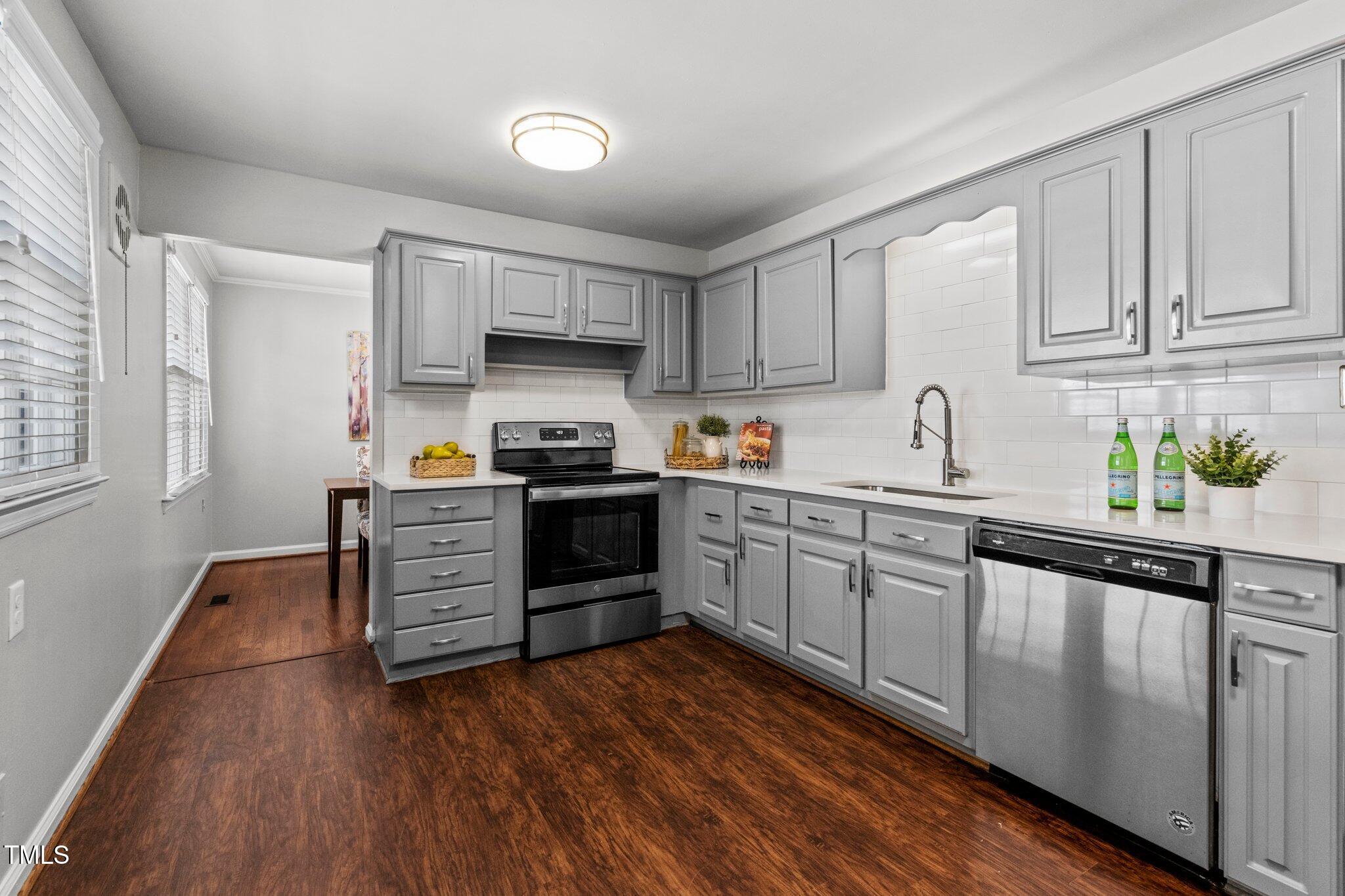 530 Banks Street Raleigh, NC 27604 - Photo 9 of 50 a kitchen with stainless steel appliances granite countertop a stove a sink dishwasher and a refrigerator with wooden floors
