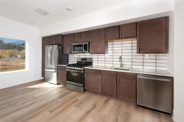 a kitchen with granite countertop stainless steel appliances cabinets a sink and a window