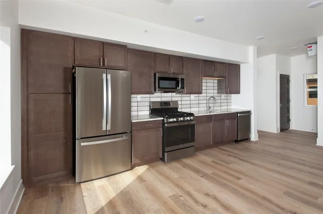 a kitchen with stainless steel appliances kitchen island granite countertop a refrigerator and a stove