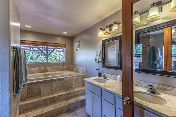 a bathroom with a tub a sink and mirror