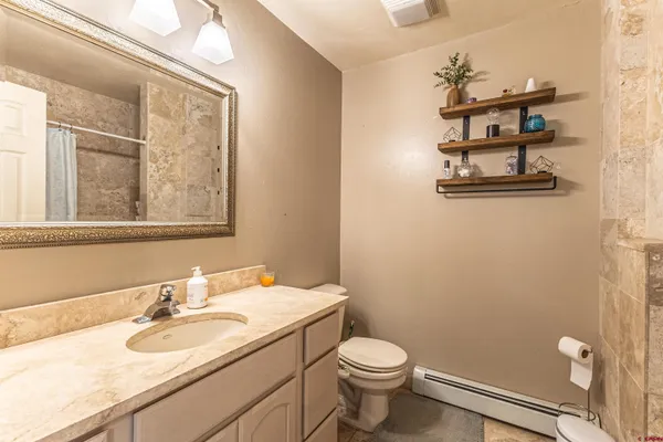 a bathroom with a granite countertop toilet sink and mirror